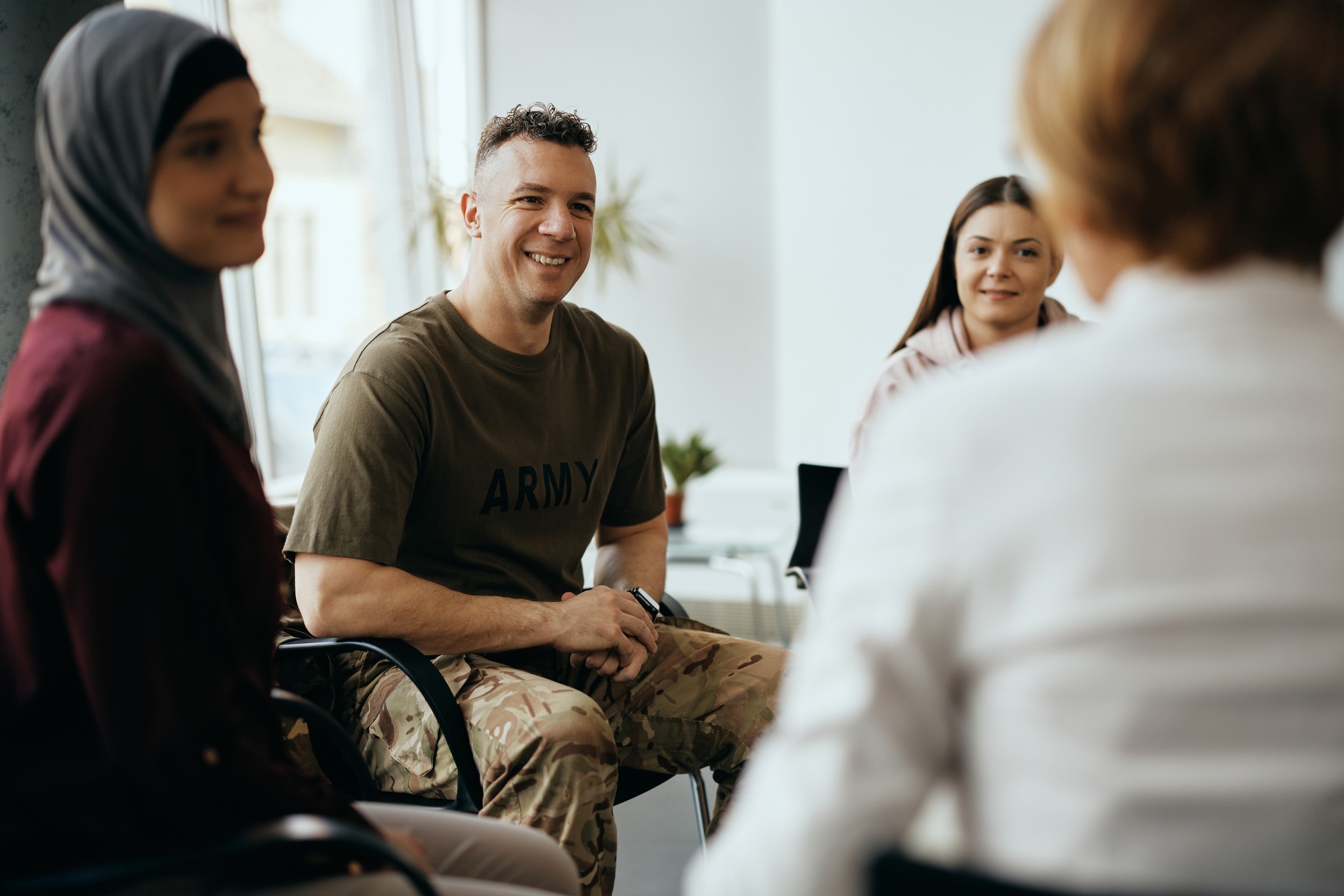 Happy soldier and group of people having group therapy at mental healthcare center.; Shutterstock ID 2138942003; purchase_order: Pro Serv; job: ; client: ; other: